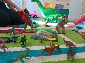 na dywanie stoją figurki różnych dinozaurów