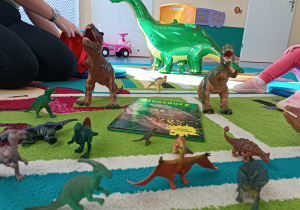 na dywanie stoją figurki różnych dinozaurów