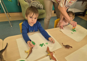 chłopiec maluje gąbką z farbą gipsowego dinozaura