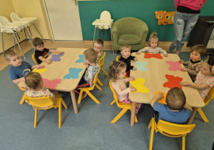 dzieci siedzą przy stolkach, każde dostało motyla wyciętego z papieru