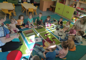 dzieci i opiekunki siedzą na dywanie i rozmawiają jak dbać o zęby