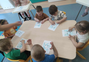 dzieci siedzą przy stoliku i wykonują pracę plastyczną