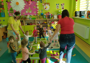 dzieci i opiekunki trzymają się za ręce i tańczą