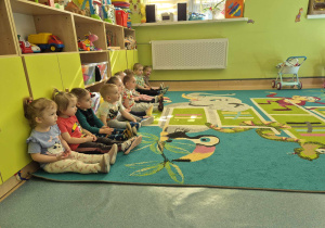 dzieci siedzą grzecznie na dywanie