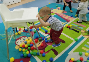 chłopiec przykleja piłeczkę do taśmy pod krzesełkiem