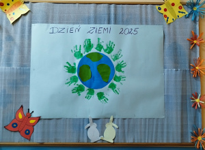 na tablicy wisi karton z zielonymi odbiciami dłoni dzieci wokół planety Ziemii
