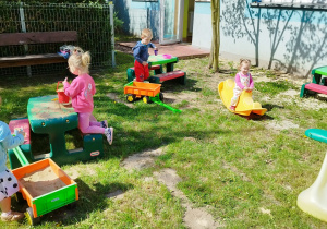dziewczynka buja się na bujaku, chłopiec trzyma kubeczek
