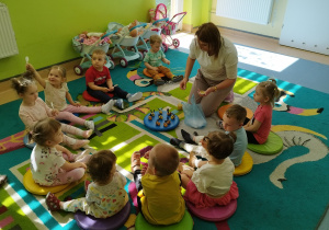 opiekunka częstuje dzieci miodem, wszyscy siedza na dywanie