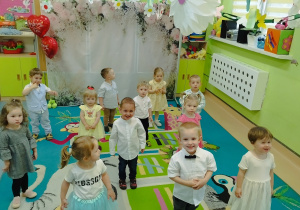 dzieci stoją na dywanie uśmiechają się