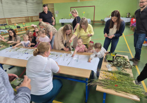 rodzice i dzieci przyklejają do kartonu kwiaty i trawy