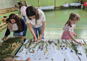 dzieci i rodzice przyklejają trawy i kwiaty