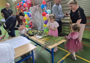 dzieci i rodzice wybierają trawy spośród naszykowanych na stoliku
