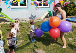 opiekunka rozdaje dzieciom balony