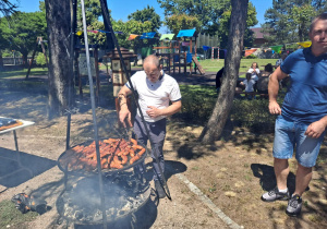 panowie pilnują kiełbasek na grillu