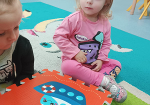 dziewczynka siedzi i słucha co mówi opiekunka