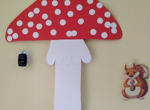 duży kartonowy muchomor, a pod nim obrazek wiewiórki