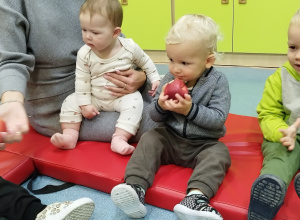 opiekunka siedzi z dziećmi, chłopiec gryzie jabłko