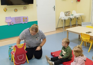 dzieci siedzą i słuchają opowiadanego wiersza przez opiekunkę