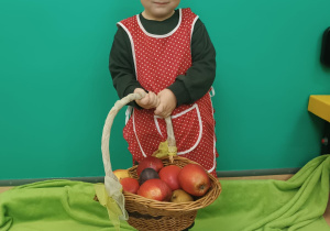 chłopiec uśmiecha się, trzyma koszyk z jabłkami