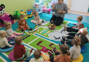 dzieci siedza na dywanie , opiekunka pokazuje kasztany, które przyniosła