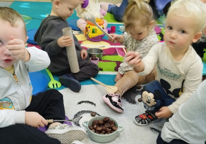 dzieci bawią się kasztanami na dywanie
