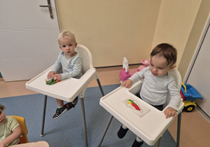 chłopcy siedzą w krzesłach , jeden gniecie woreczek , a drugi patrzy