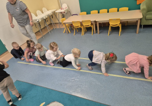 dzieci czworakują między liniami jedno za drugim