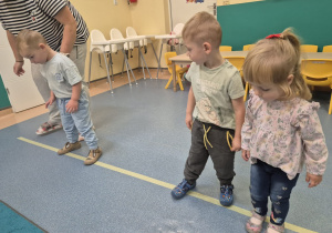 dzieci idą bokiem po linii
