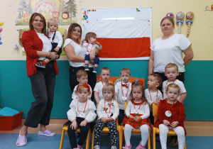 dzieci i opiekunki pozują do zdjęcia z flagą Polski