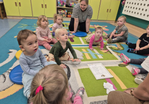 dzieci z opiekunką siedzą na dywanie słuchają co mówi o jeżu