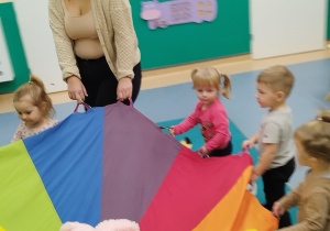 dzieci trzymają chustę na której leżą misie i kręcą się w koło