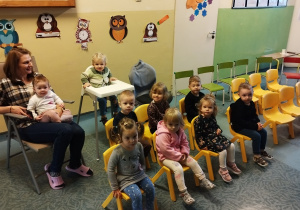 dzieci siedzą na krzesłach i opiekunka, czekają na przedstawienie