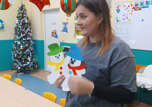 opiekunka trzyma w rękach papierowe bałwanki