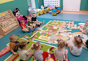 dzieci siedzą na dywanie aa przed nimi ułożona rozsypanka obrazkowa