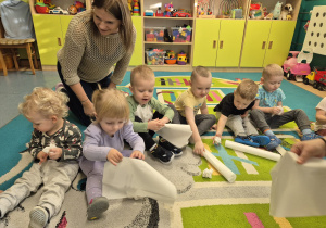 dzieci i opiekunka gniotą papier robiąc kulki