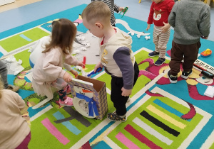 dzieci wkładają za pomocą pęset papierowe kulki do pudełka