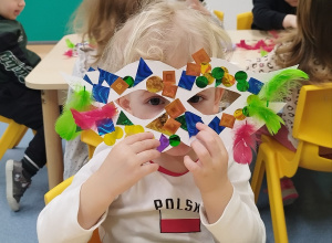 dziecko pokazuje udekorowaną przez siebie maskę
