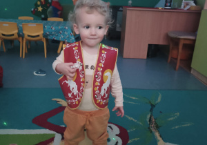chłopiec w kamizelce z konikiem uśmiecha się