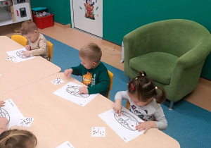dzieci siedzą przy stoliku i wykonują pracę plastyczną