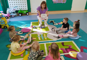 dzieci siedzą na dywanie , opiekunka pokazuje ilustrację smutnego ząbka i tego co mu szkodzi