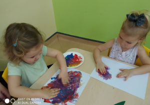 dziewczynki malują rękami na kartce