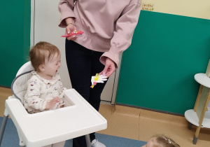 opiekunka pokazuje dziewczynce wykonaną kurkę, dziewczynka uśmiecha się