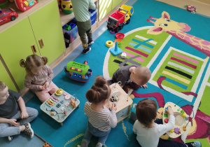 dzieci siedzą na dywanie i bawią się zabawkami