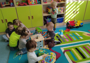 dzieci na dywanie bawią się stolikami edukacyjnymi