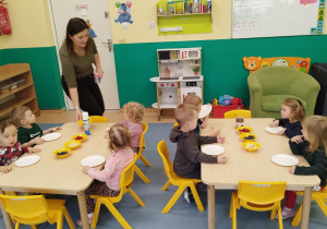 dzieci siedzą przy stolikach, przed nimi leżą gofry i dodatki