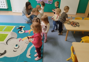 dzieci zapinają spinacze do sznurka, opiekunka pomaga