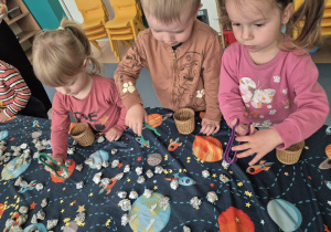 dzieci przy użyciu pęset zbierają kamyki