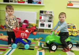 Ksawery wozi pieska w wózku na zakup, a Patryk jeździ na motorku.