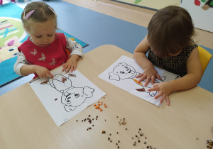 dzieci siedzące przy stoliku wyklejają kontury psa kulkami plasteliny