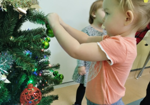 dziewczynka zawiesza bombkę na gałązce